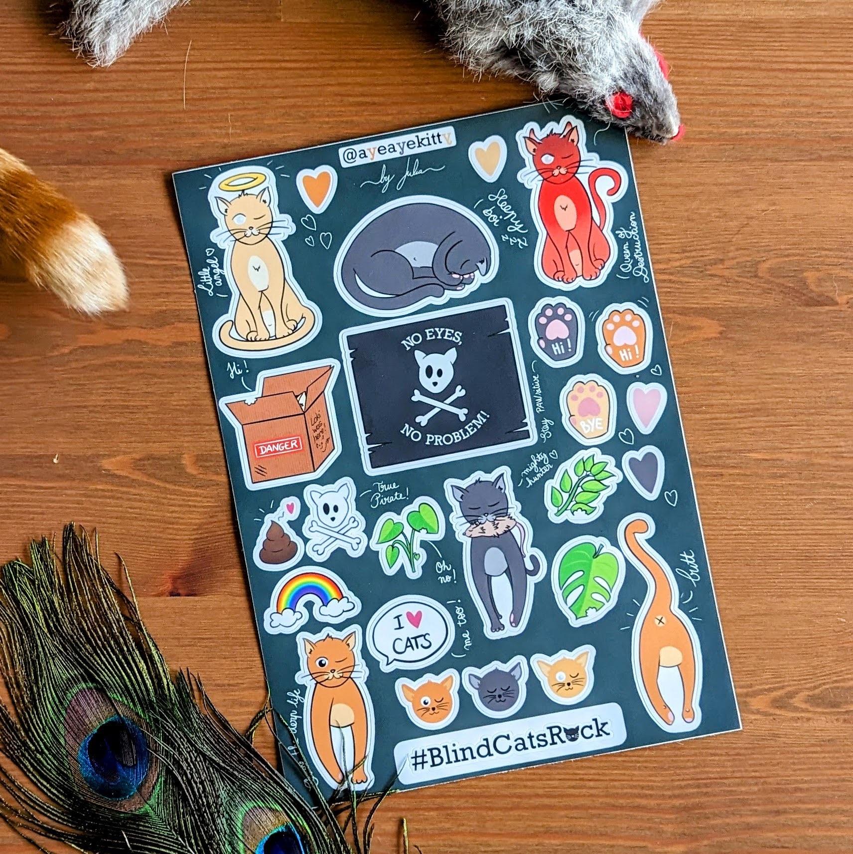 a sheet of stickers in a doodle style, including the three cats, some half eaten plants, and damages card box, some paws, some hearts, a pirate flag, a poop, and a rainbow